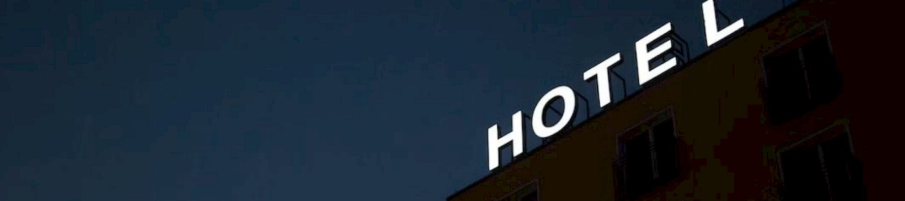 A building with a partially lit "HOTEL" sign against a dark sky, missing the letter "L".