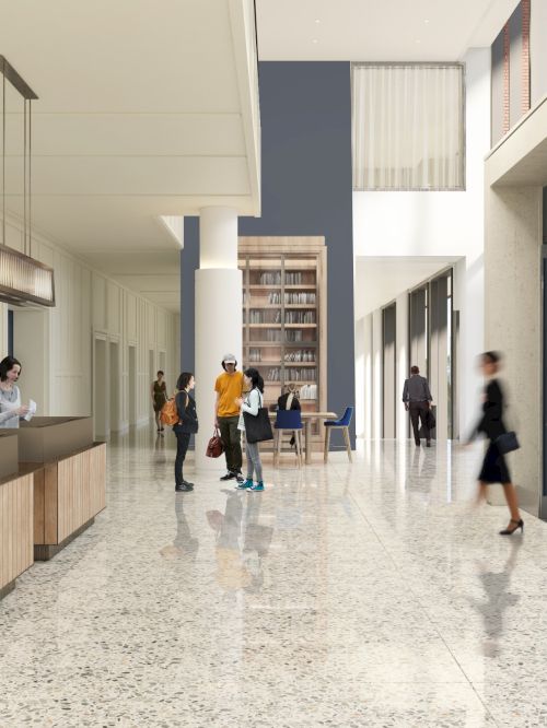 A modern lobby with people interacting by a reception desk, featuring sleek design elements, art, and large windows for natural light.