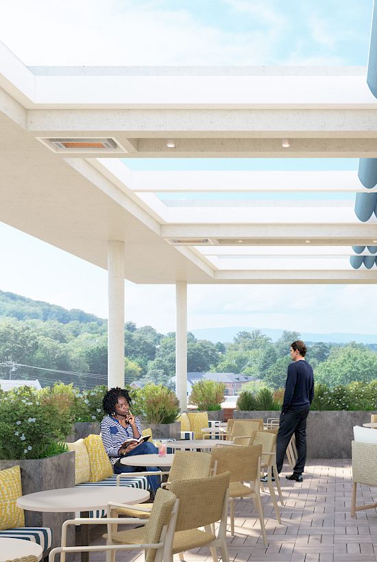 An outdoor terrace with people seated at tables, surrounded by greenery and large open skylights above, under a partly cloudy sky.