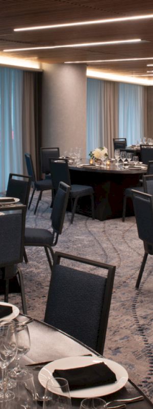 A banquet hall with round tables set for dining, featuring elegant tableware, black napkins, and floral centerpieces.